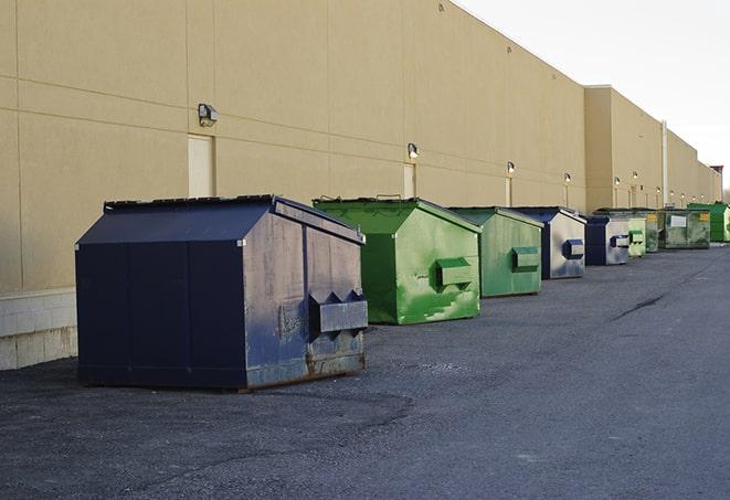 a construction worker unloading debris into a blue dumpster in Vermilion, OH